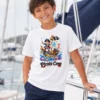 Chłopiec na jachcie w białej koszulce pirackiej dziecięcej Pirate Crew ze statkiem i banderą — NAVI Kids